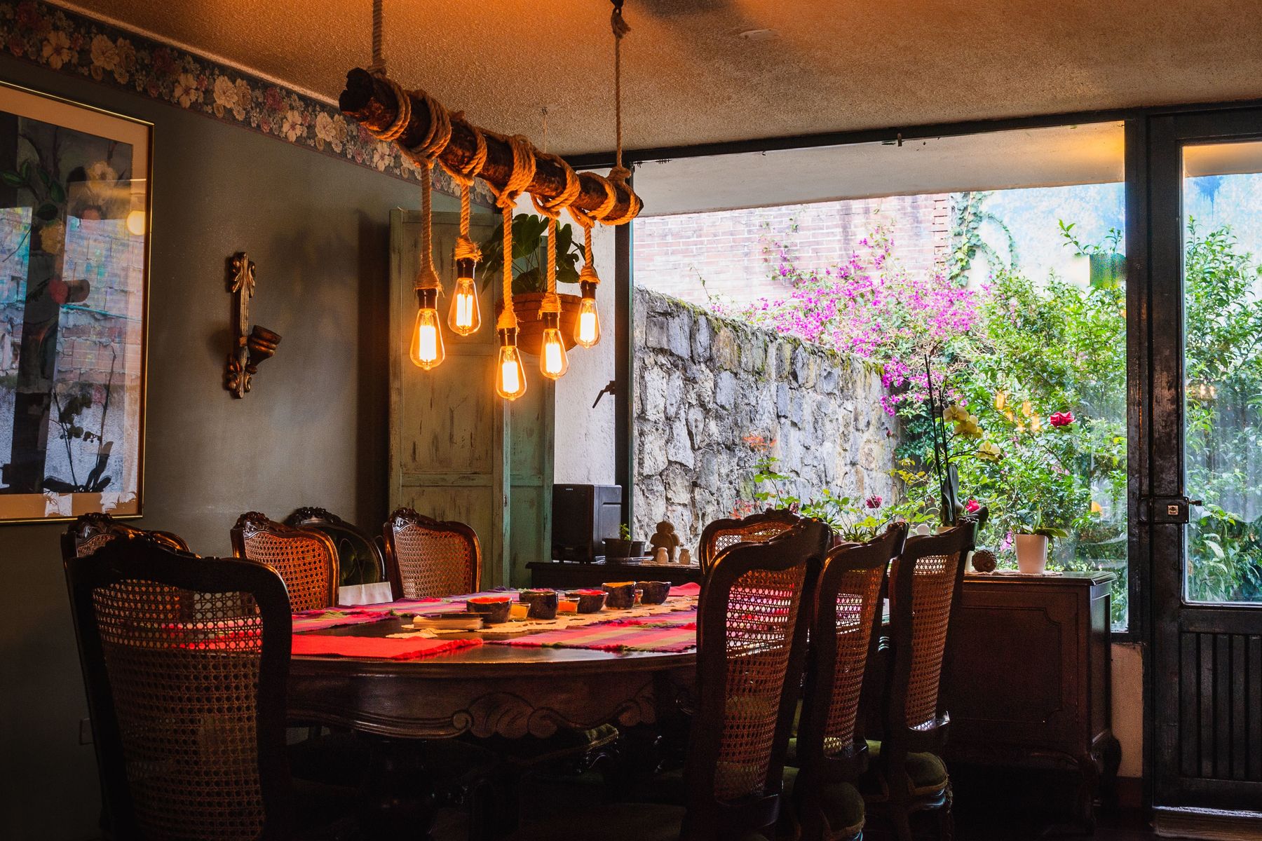 Rustic dining table under a chandelier of ropes and bulbs